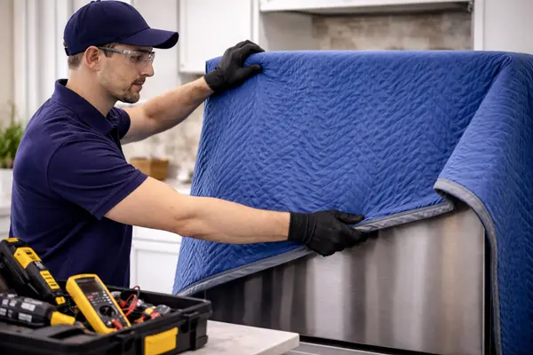 an appliance repair technician protecting a kitchen appliance with a padded moving blanket during service from Appliance Repair Leander in Katy, TX - Katy TX an appliance repair technician protecting a kitchen appliance with a padded moving blanket during service from Appliance Repair Leander in Katy, TX - Katy TX